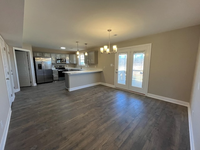 kitchen featuring dark wood-type flooring, an inviting chandelier, hanging light fixtures, stainless steel appliances, and kitchen peninsula