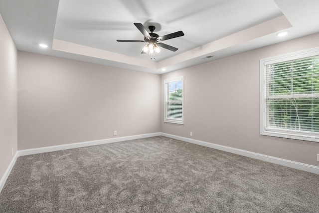 unfurnished room with ceiling fan, carpet flooring, and a raised ceiling