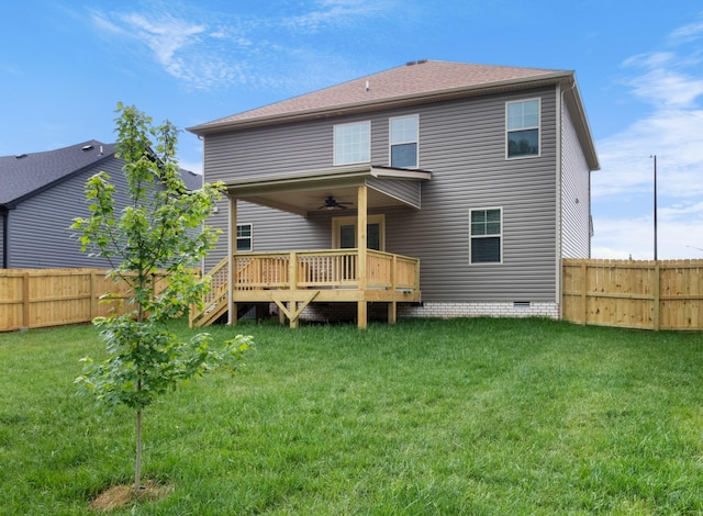 back of property with a wooden deck, ceiling fan, and a yard