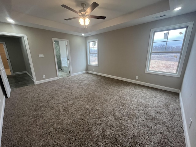 carpeted empty room featuring ceiling fan and a raised ceiling