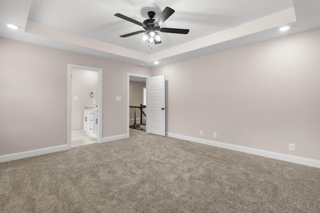 unfurnished bedroom with ceiling fan, light colored carpet, and a raised ceiling