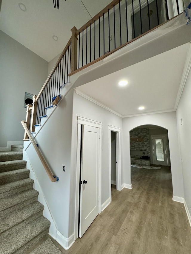 staircase with crown molding and wood-type flooring