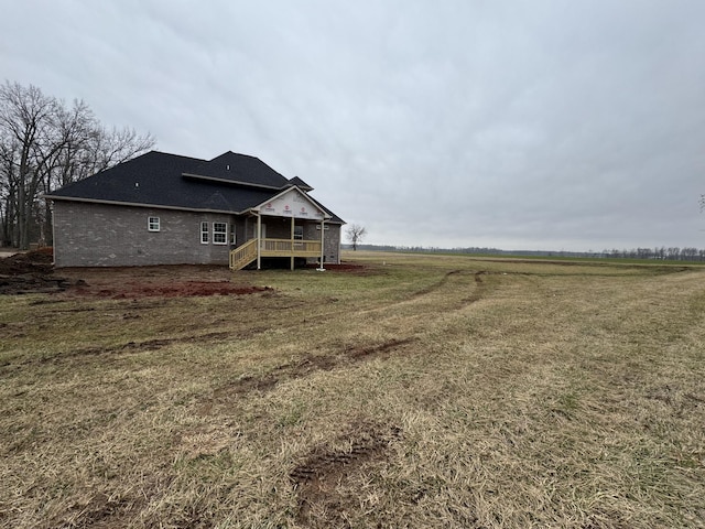 rear view of property with a rural view and a lawn