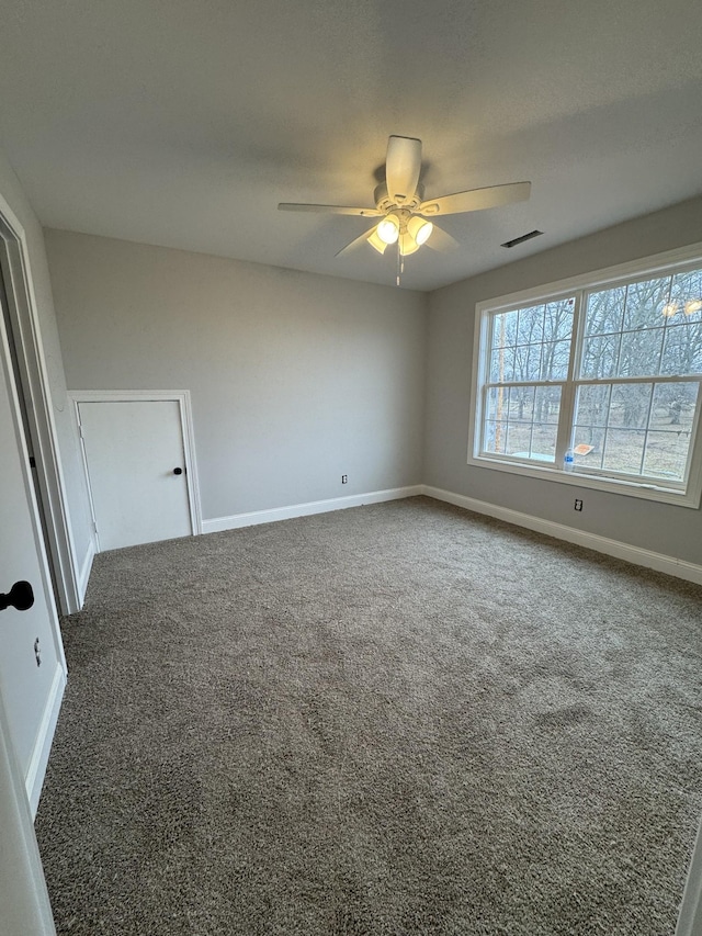 empty room with ceiling fan and dark carpet