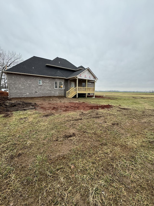 back of house with a wooden deck, a lawn, and a rural view