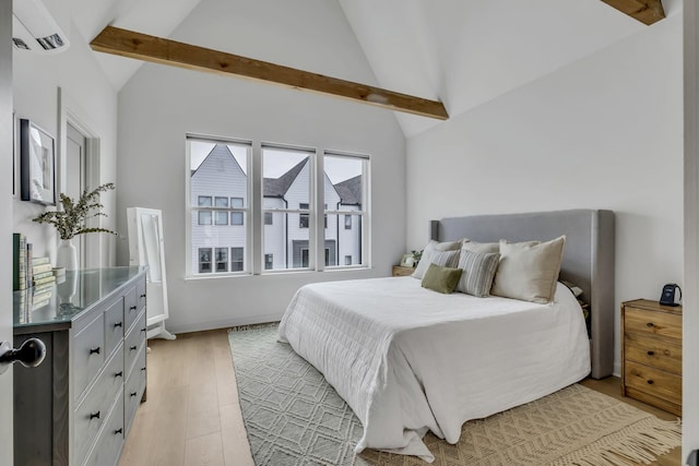 bedroom featuring vaulted ceiling with beams, light hardwood / wood-style floors, and an AC wall unit