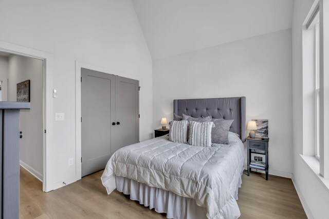 bedroom featuring light hardwood / wood-style flooring, vaulted ceiling, and a closet