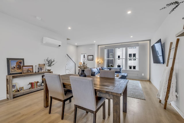 dining area with light hardwood / wood-style flooring and an AC wall unit