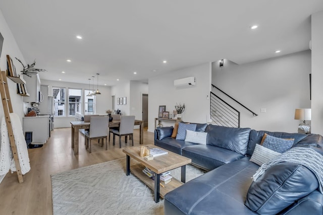 living room with a wall mounted AC and light wood-type flooring