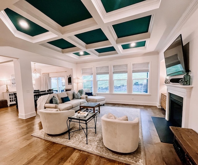 living room with hardwood / wood-style flooring, an inviting chandelier, coffered ceiling, ornamental molding, and beamed ceiling