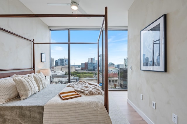 bedroom featuring ceiling fan, a wall of windows, and wood-type flooring