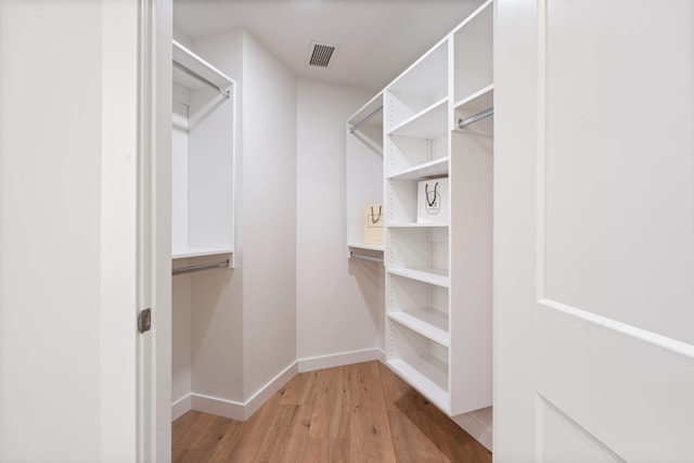 walk in closet with light hardwood / wood-style flooring