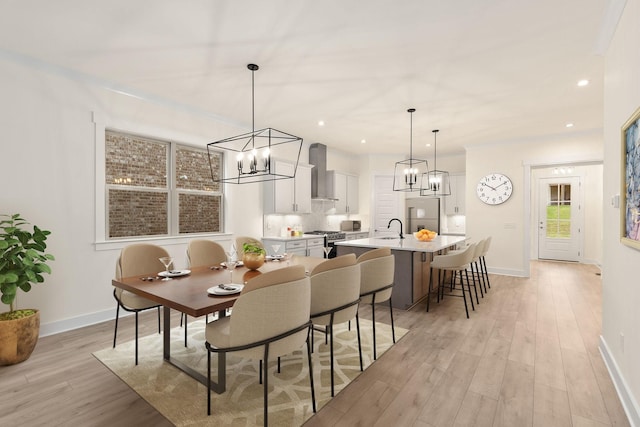 dining space featuring sink, an inviting chandelier, and light hardwood / wood-style floors