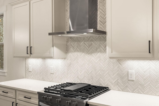 kitchen with tasteful backsplash, wall chimney exhaust hood, and range with gas cooktop