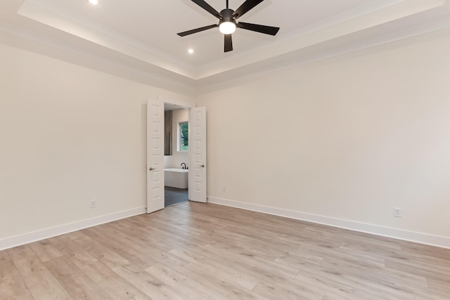 spare room with ceiling fan, a raised ceiling, and light hardwood / wood-style flooring