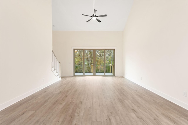 unfurnished living room featuring ceiling fan, light hardwood / wood-style floors, and a high ceiling