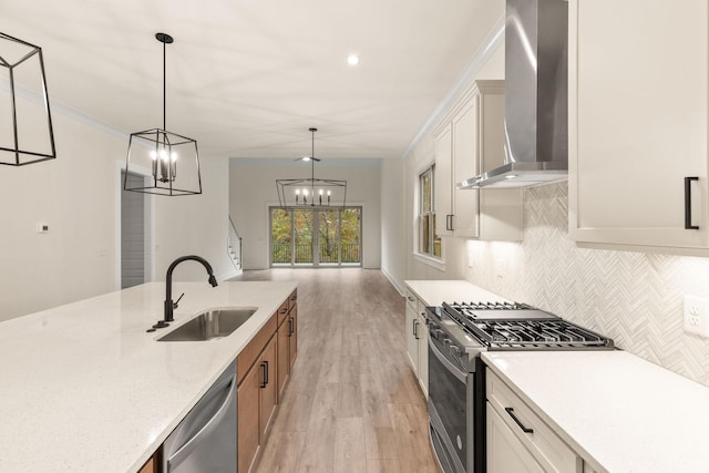 kitchen featuring pendant lighting, sink, backsplash, stainless steel appliances, and wall chimney range hood