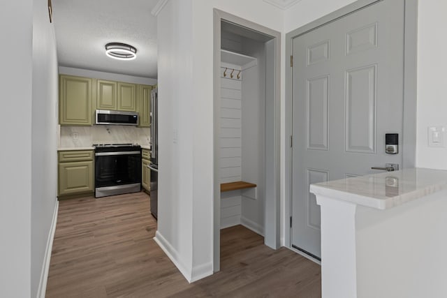 kitchen featuring tasteful backsplash, green cabinetry, light wood-type flooring, kitchen peninsula, and stainless steel appliances