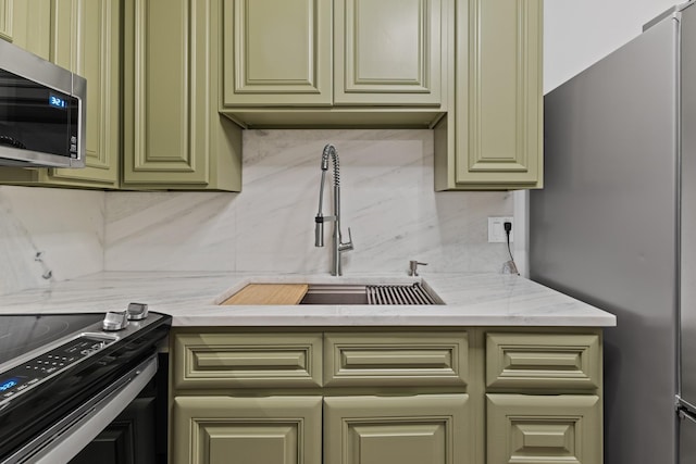 kitchen with light stone counters, appliances with stainless steel finishes, sink, and decorative backsplash