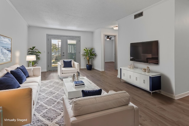 living room featuring ornamental molding, a textured ceiling, dark hardwood / wood-style flooring, and french doors