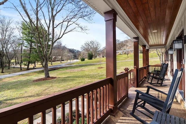 wooden terrace featuring a lawn and a porch