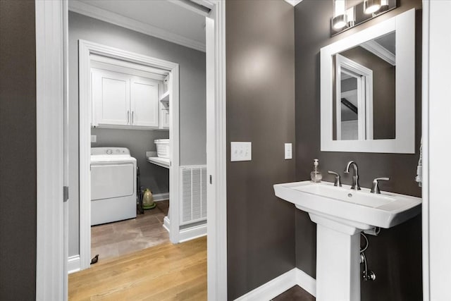 bathroom featuring sink, ornamental molding, washer / clothes dryer, and hardwood / wood-style floors