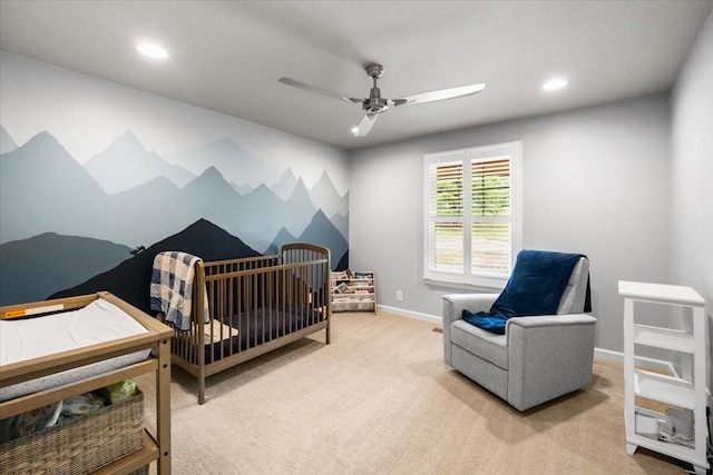 bedroom with ceiling fan, light carpet, and a crib