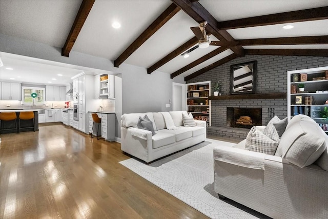 living room with lofted ceiling with beams, ceiling fan, dark hardwood / wood-style floors, and a fireplace