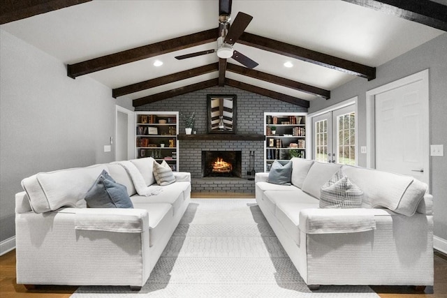 living room with ceiling fan, vaulted ceiling with beams, hardwood / wood-style floors, a brick fireplace, and french doors