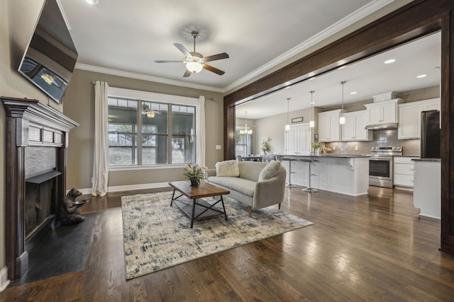 living room featuring ornamental molding, dark wood-type flooring, and ceiling fan with notable chandelier