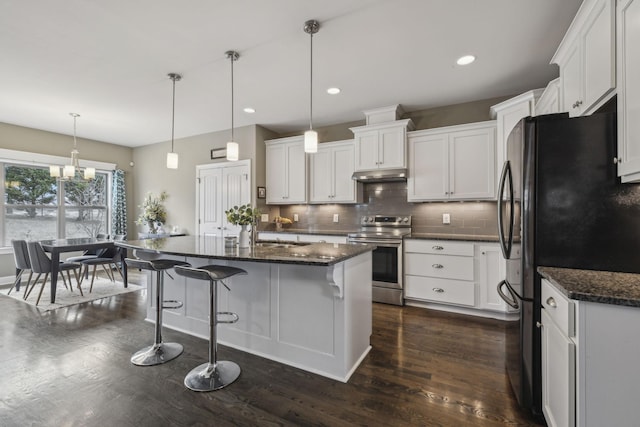 kitchen with stainless steel electric stove, white cabinetry, hanging light fixtures, fridge, and a center island