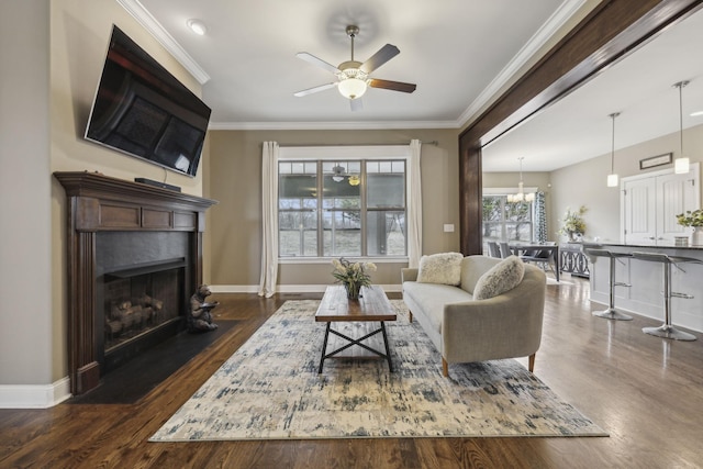 living room with crown molding, dark wood-type flooring, and ceiling fan with notable chandelier