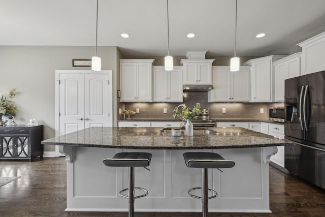 kitchen featuring white cabinetry, black fridge with ice dispenser, an island with sink, and hanging light fixtures