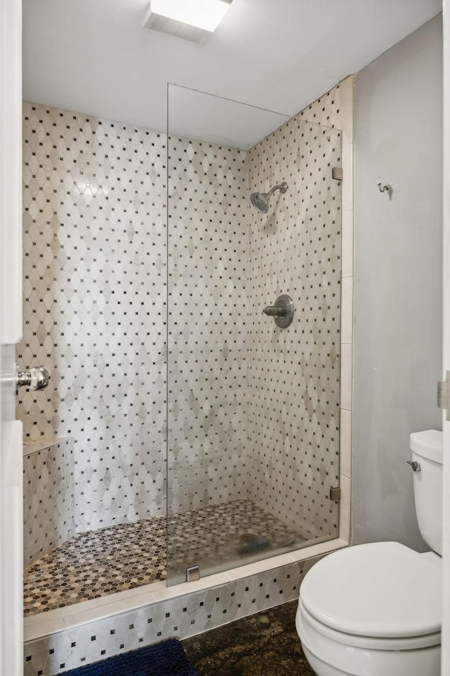 bathroom featuring a tile shower and toilet