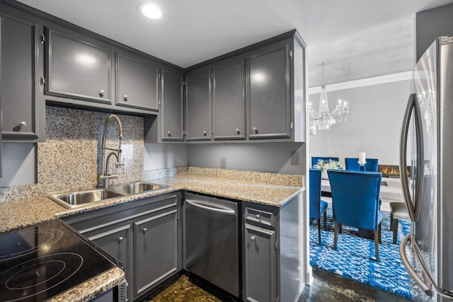 kitchen with light stone counters, stainless steel appliances, sink, and a notable chandelier