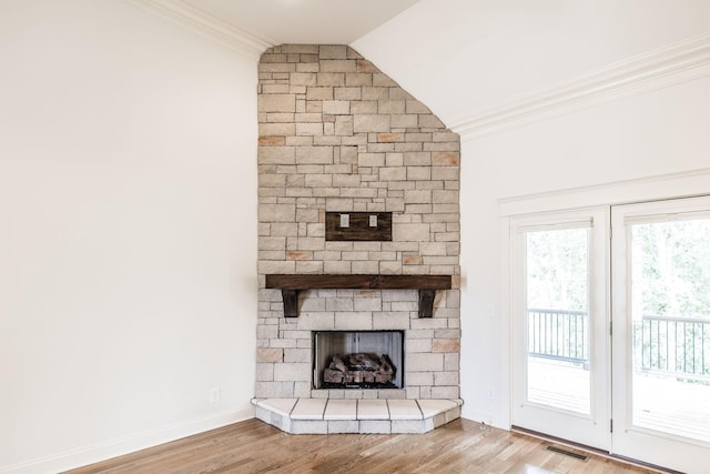 unfurnished living room featuring lofted ceiling, a fireplace, wood finished floors, visible vents, and ornamental molding