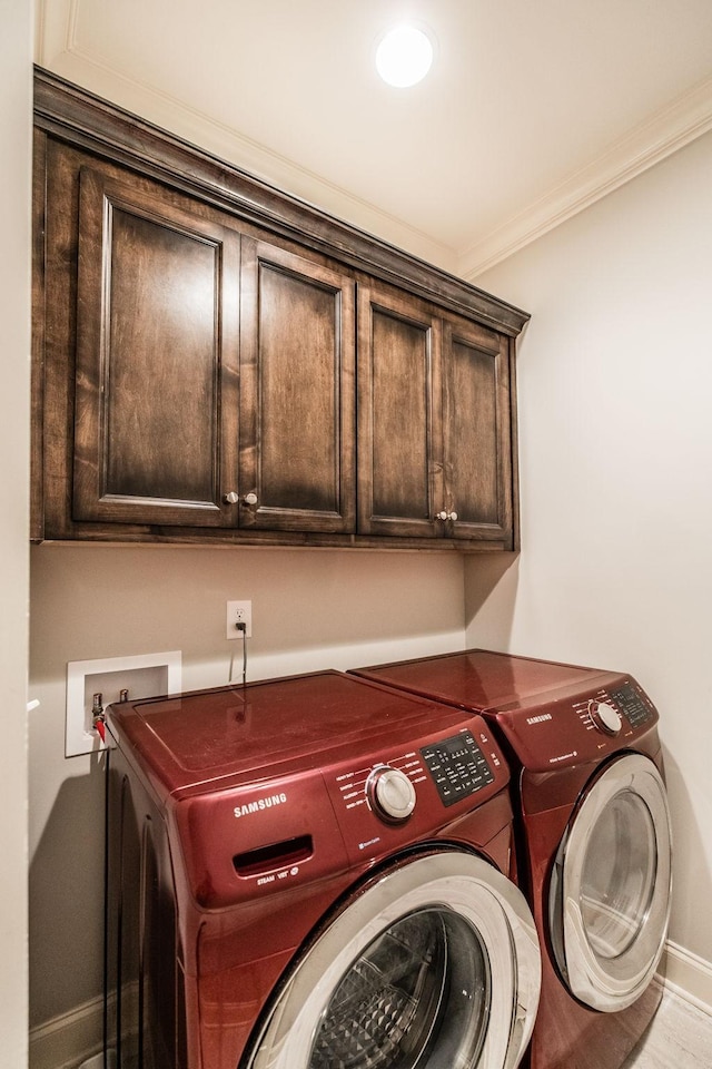 clothes washing area featuring washing machine and dryer, cabinet space, crown molding, and baseboards