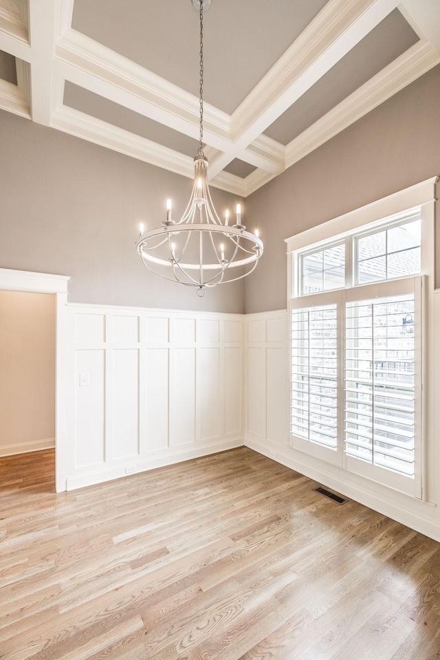 unfurnished dining area with crown molding, light hardwood / wood-style flooring, an inviting chandelier, coffered ceiling, and beamed ceiling