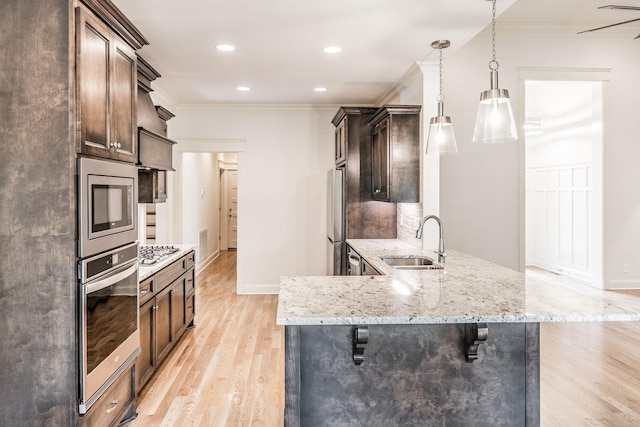 kitchen featuring light wood-style floors, ornamental molding, stainless steel appliances, and a sink