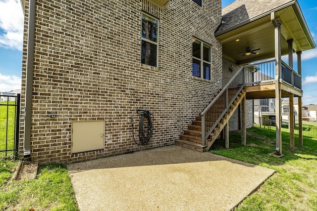 exterior space featuring ceiling fan, brick siding, fence, a lawn, and a patio area