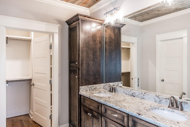 bathroom with double vanity, crown molding, a sink, and wood finished floors