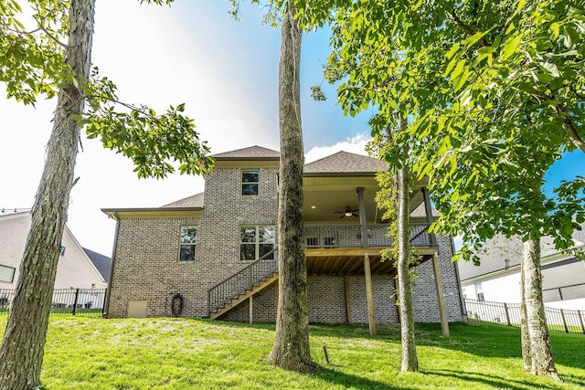 back of house featuring brick siding, stairway, a ceiling fan, and a yard