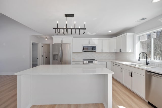 kitchen with a kitchen island, stainless steel appliances, a sink, and tasteful backsplash