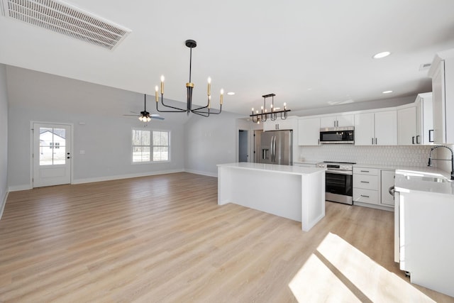 kitchen featuring decorative backsplash, visible vents, appliances with stainless steel finishes, a sink, and light countertops