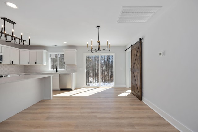 unfurnished dining area with visible vents, a barn door, a sink, a notable chandelier, and recessed lighting
