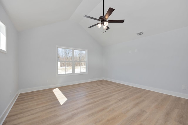 unfurnished room with visible vents, light wood-style flooring, lofted ceiling, and a wealth of natural light
