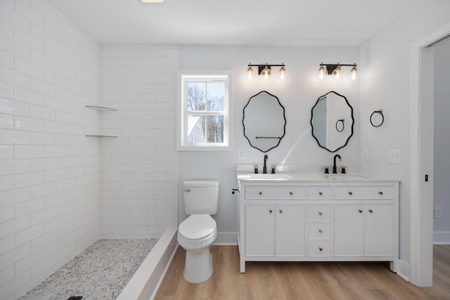 bathroom featuring double vanity, toilet, a sink, and wood finished floors