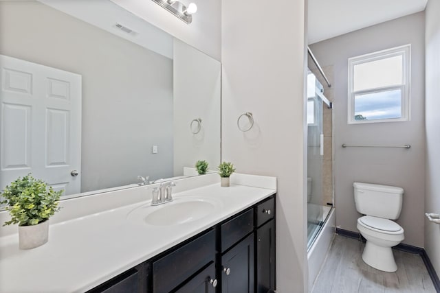 full bathroom featuring toilet, vanity, bath / shower combo with glass door, and wood-type flooring