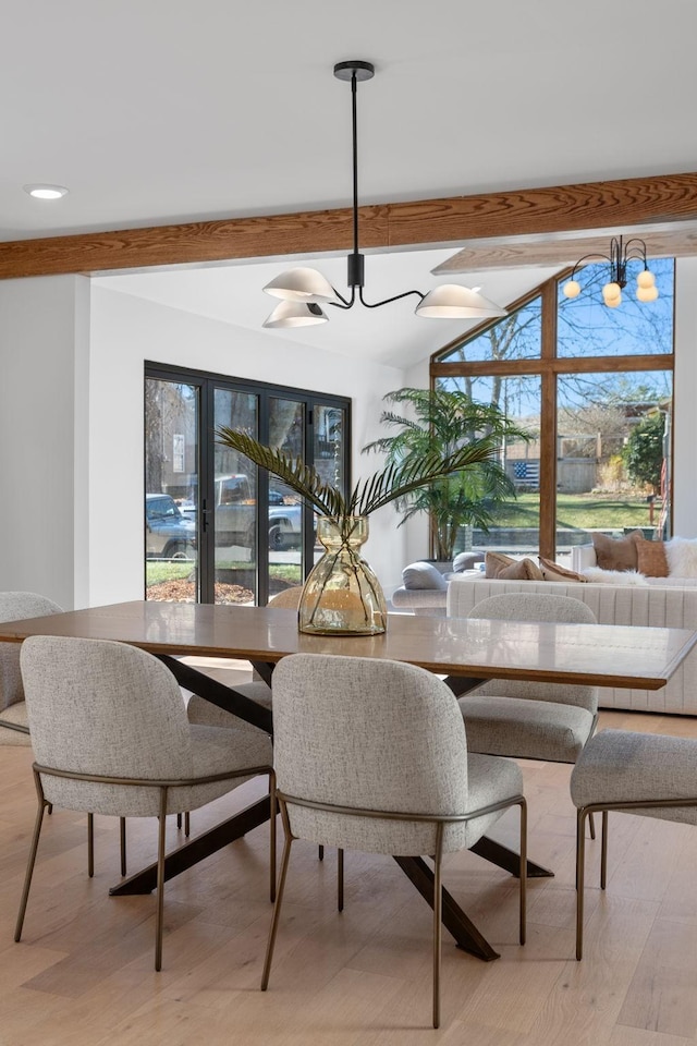 dining space with lofted ceiling with beams, light wood-type flooring, and an inviting chandelier