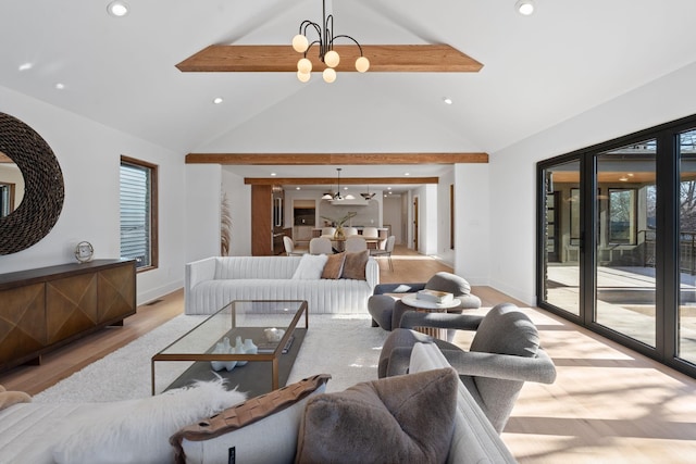 living room with a chandelier, high vaulted ceiling, and light hardwood / wood-style flooring